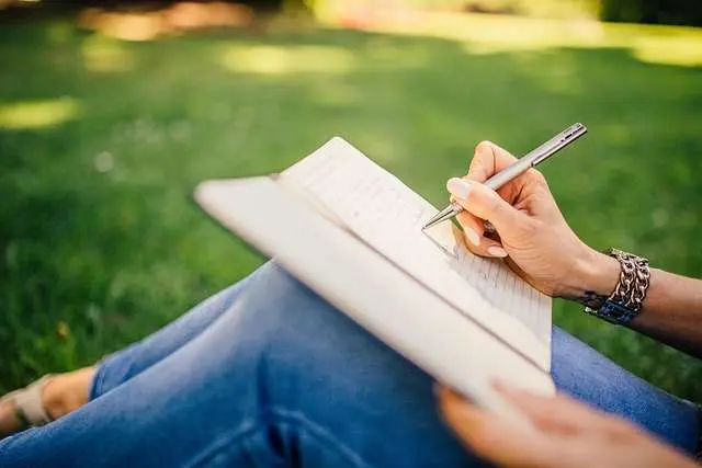 Iemand schrijft buiten in een notitieboek